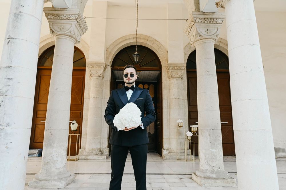 A panoramic view of a wedding couple dancing in an elegant outdoor courtyard surrounded by white columns.