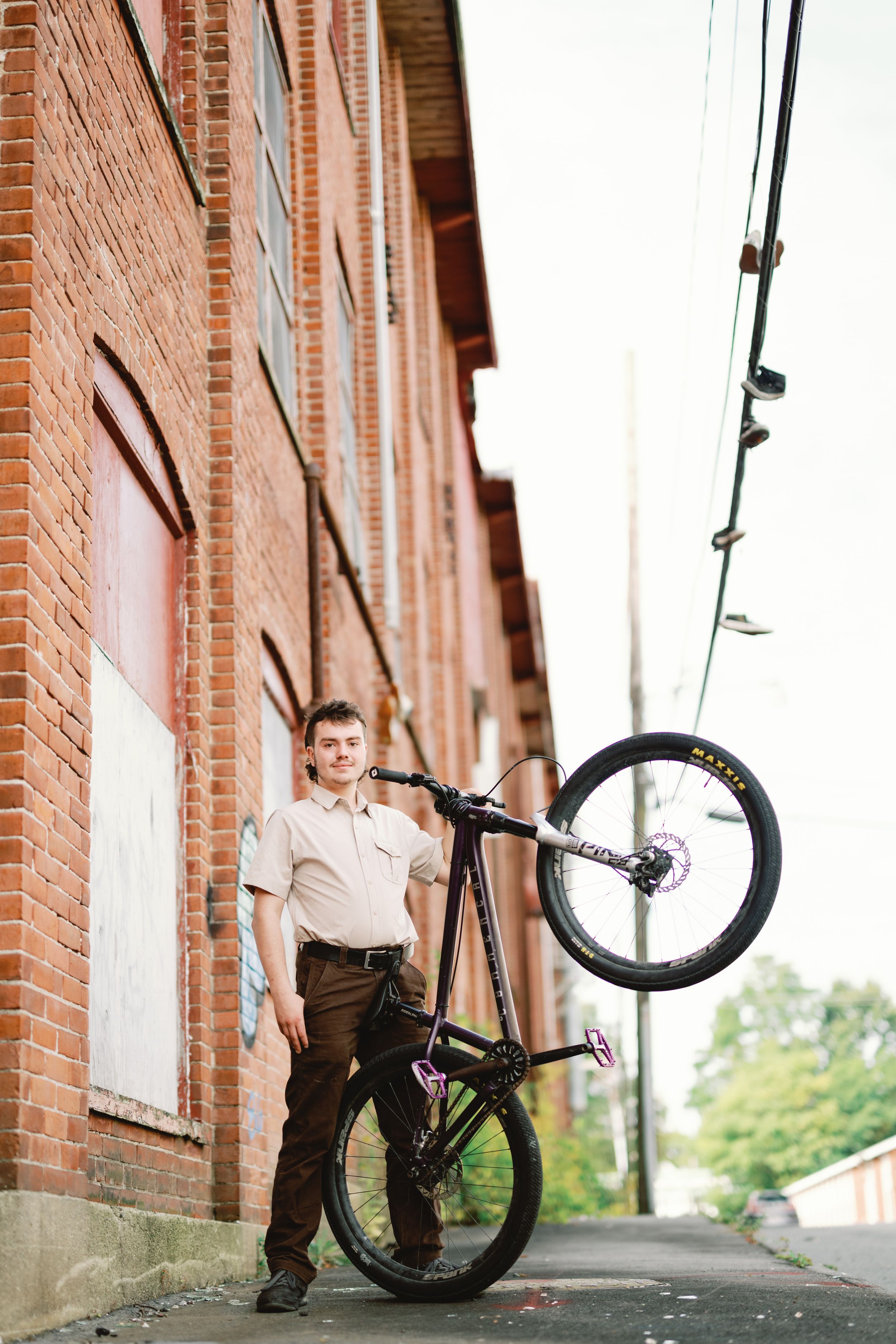 BMX cyclist performs impressive bicycle tricks in sequence against brick wall background in urban setting.