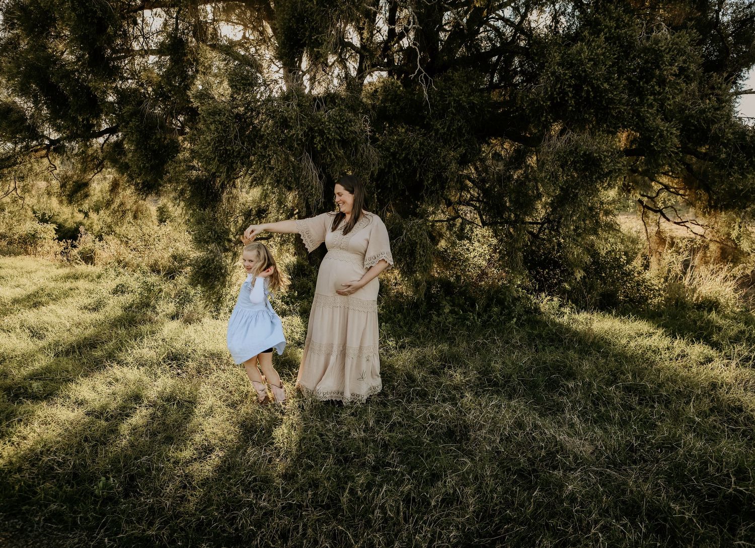Romantic sunset maternity photoshoot showing expecting couple in golden light among trees.