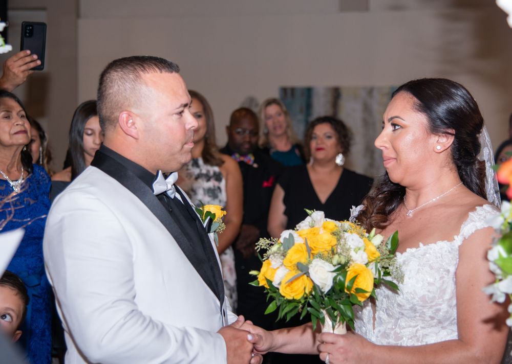Wedding couple shares their first dance surrounded by guests at a reception hall.