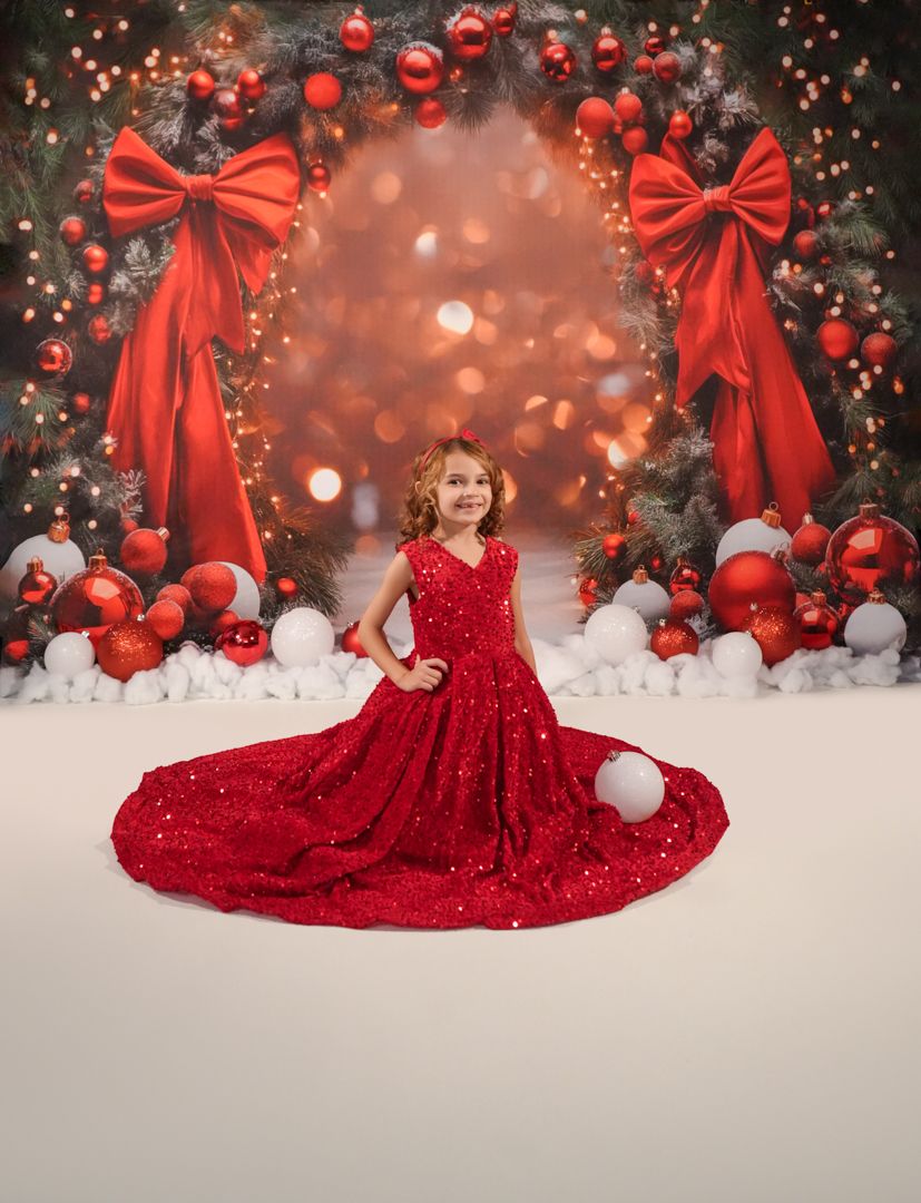 Sparkling red sequin gown displayed against a Christmas themed background with ornaments and white snowballs.