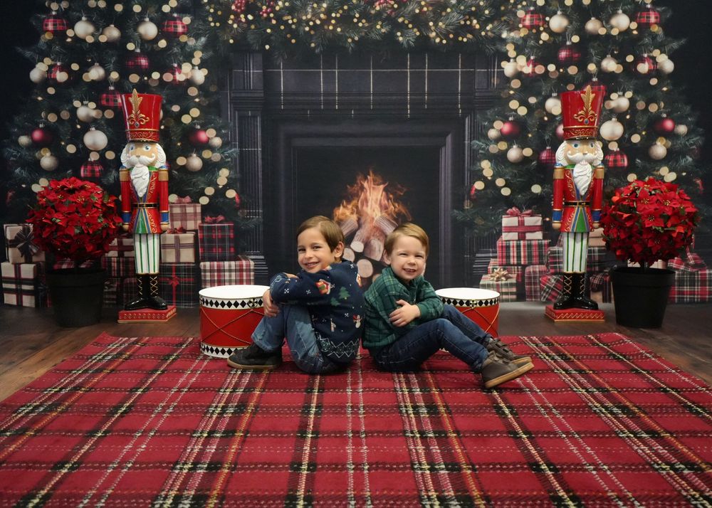 Holiday photo session setup with plaid blanket, string lights, and Christmas decorations against dark backdrop.