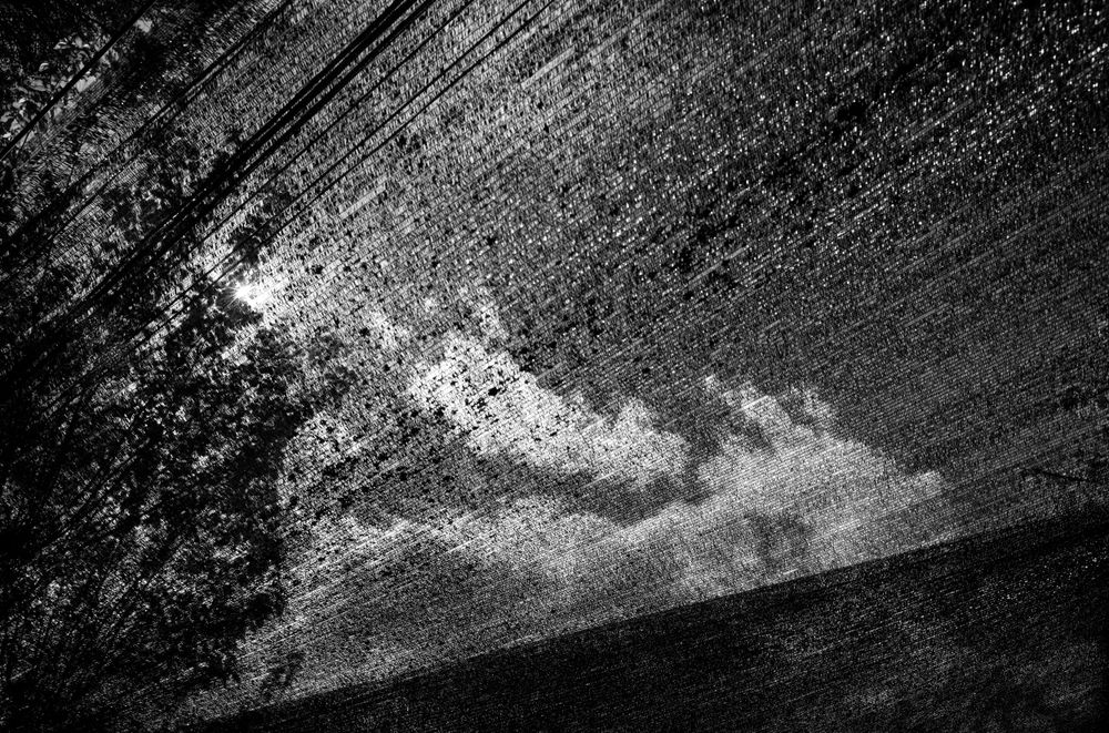 Abstract diagonal pattern of rain or water droplets against a dramatic cloudy sky.