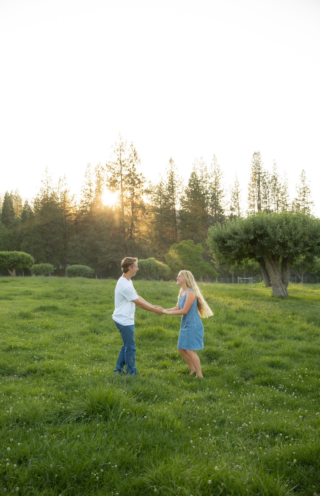 a couple nose-to-nose with the sun glistening behind them in natural colors. engagement photography