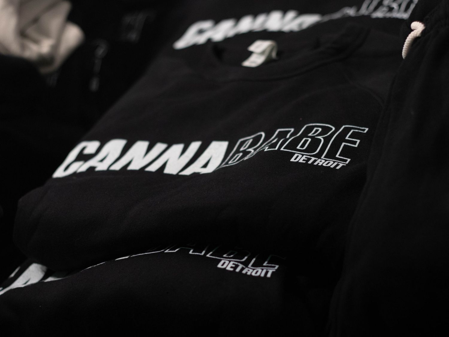 Close-up shot of black clothing items with 'CANNA' text printed on them.