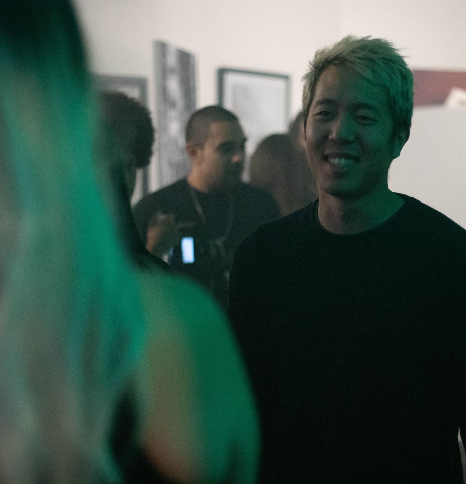 People gathered in a dimly lit room with green lighting effects.