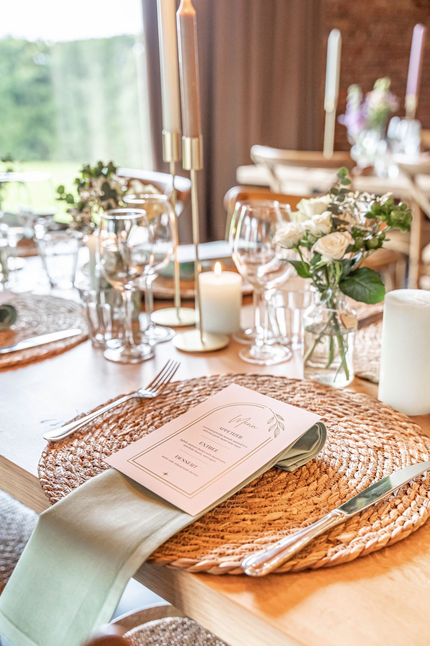 Wedding table decor with mint napkins, woven placemats, white candles and delicate floral centerpieces.