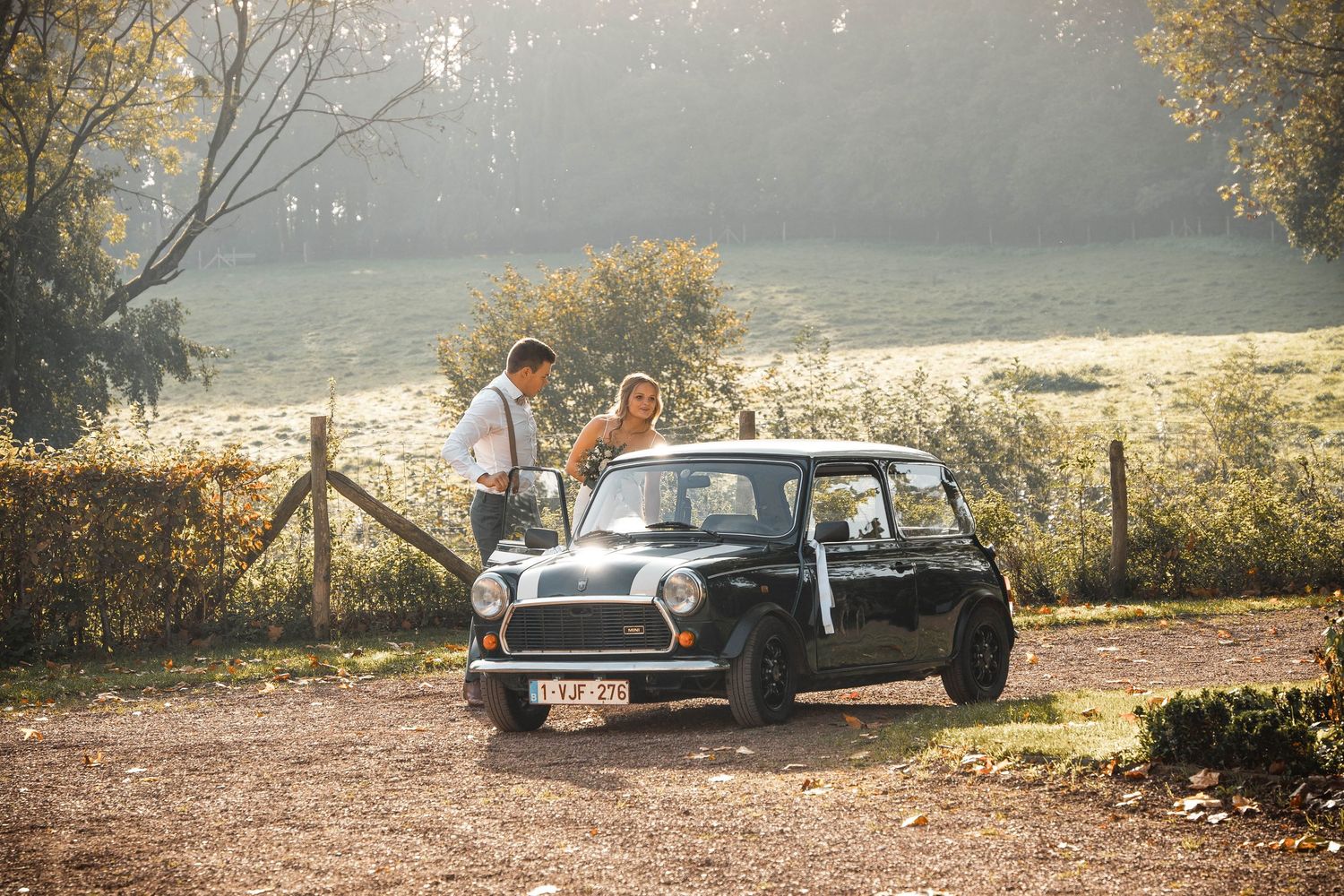 Classic Mini Cooper parked on a gravel path with golden autumn foliage in the background.