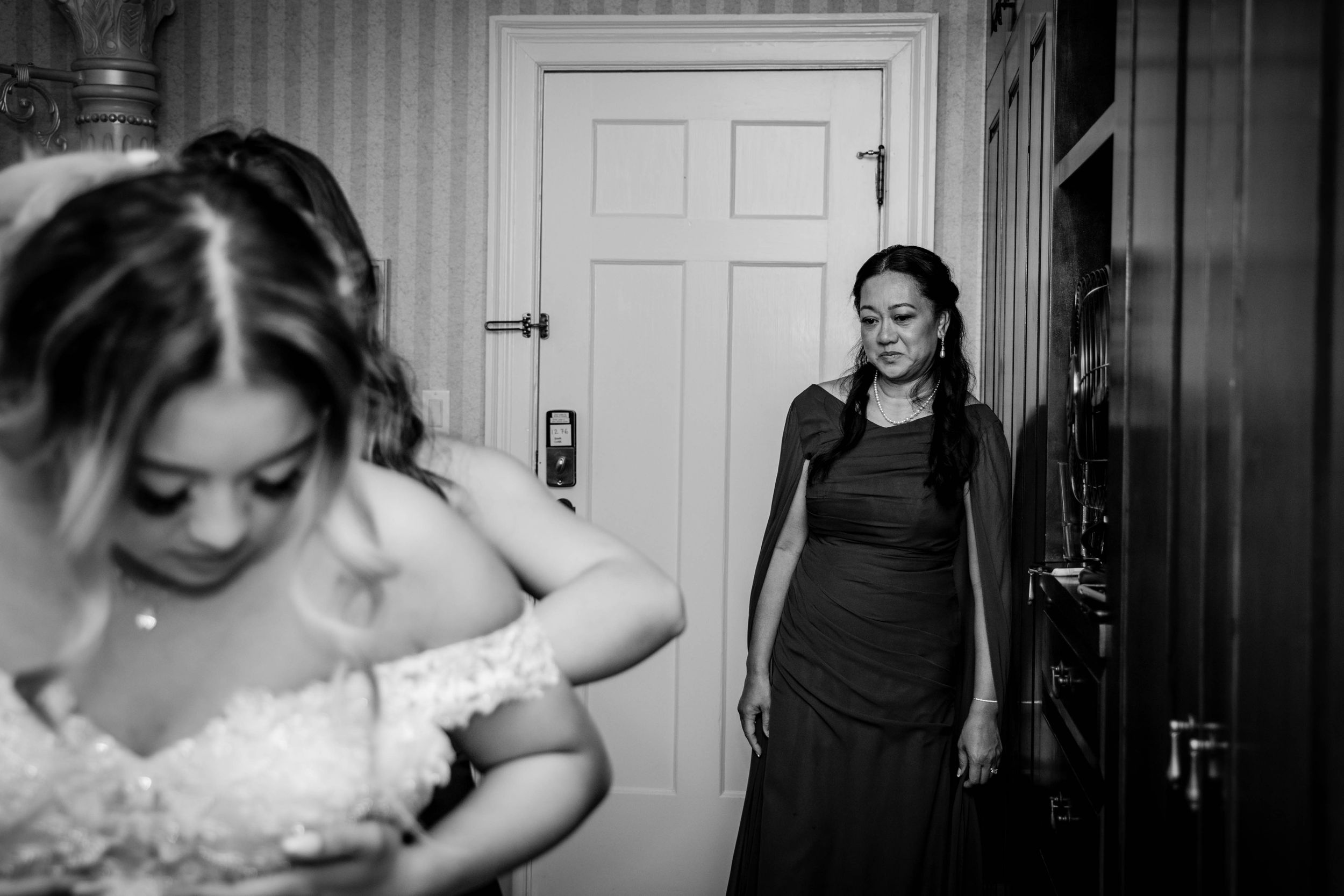 brides mom watching as she gets on her wedding dress