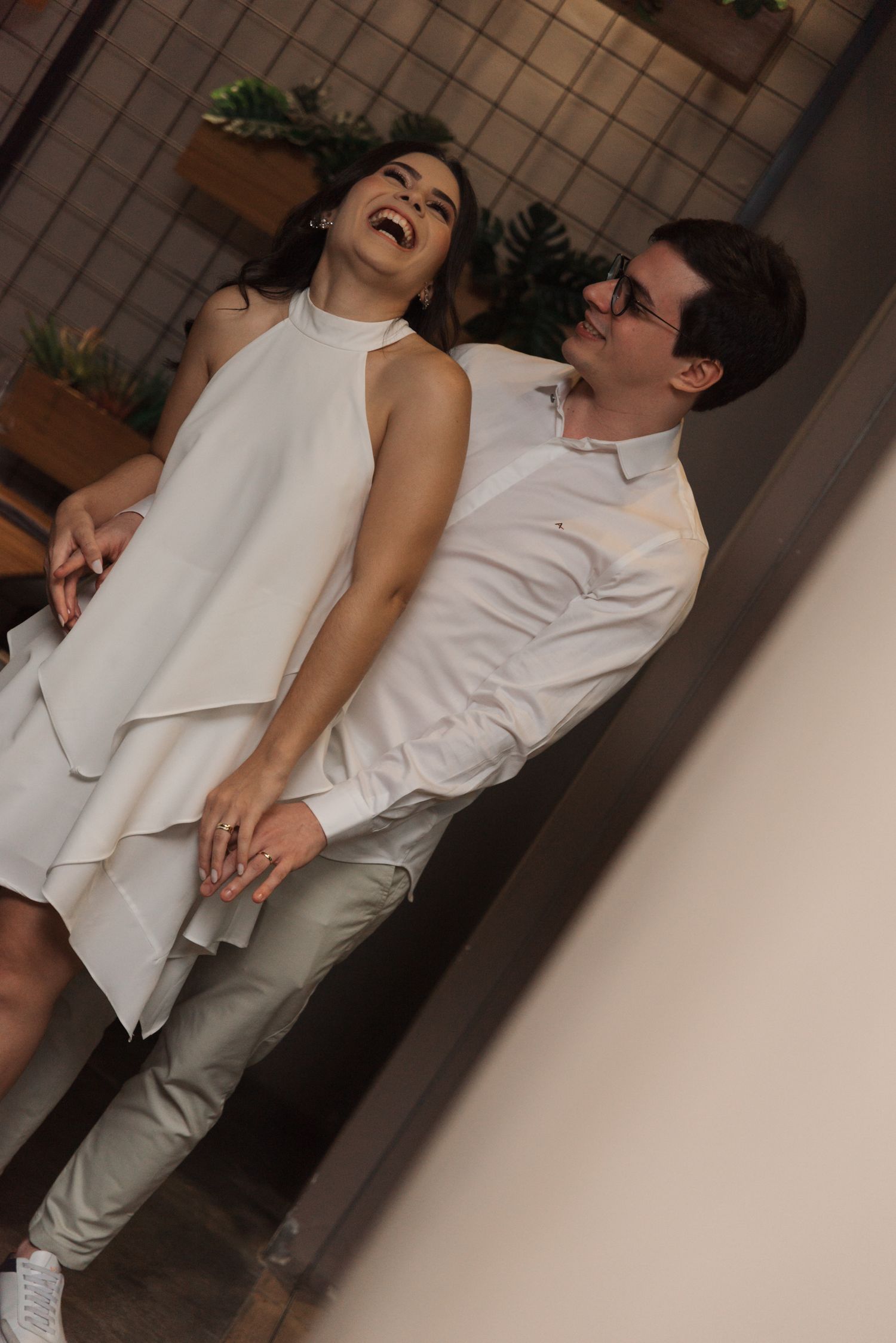 A candid moment of laughter in white attire against an urban backdrop.