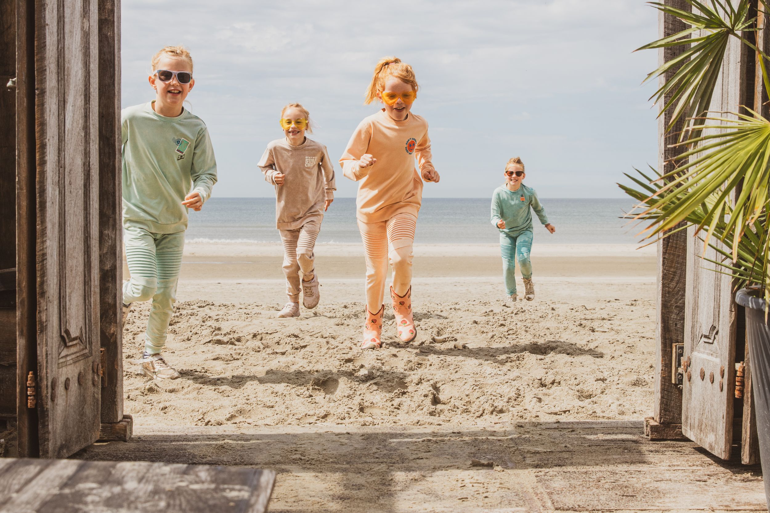 Children in colorful outfits jumping and playing on a sandy beach.