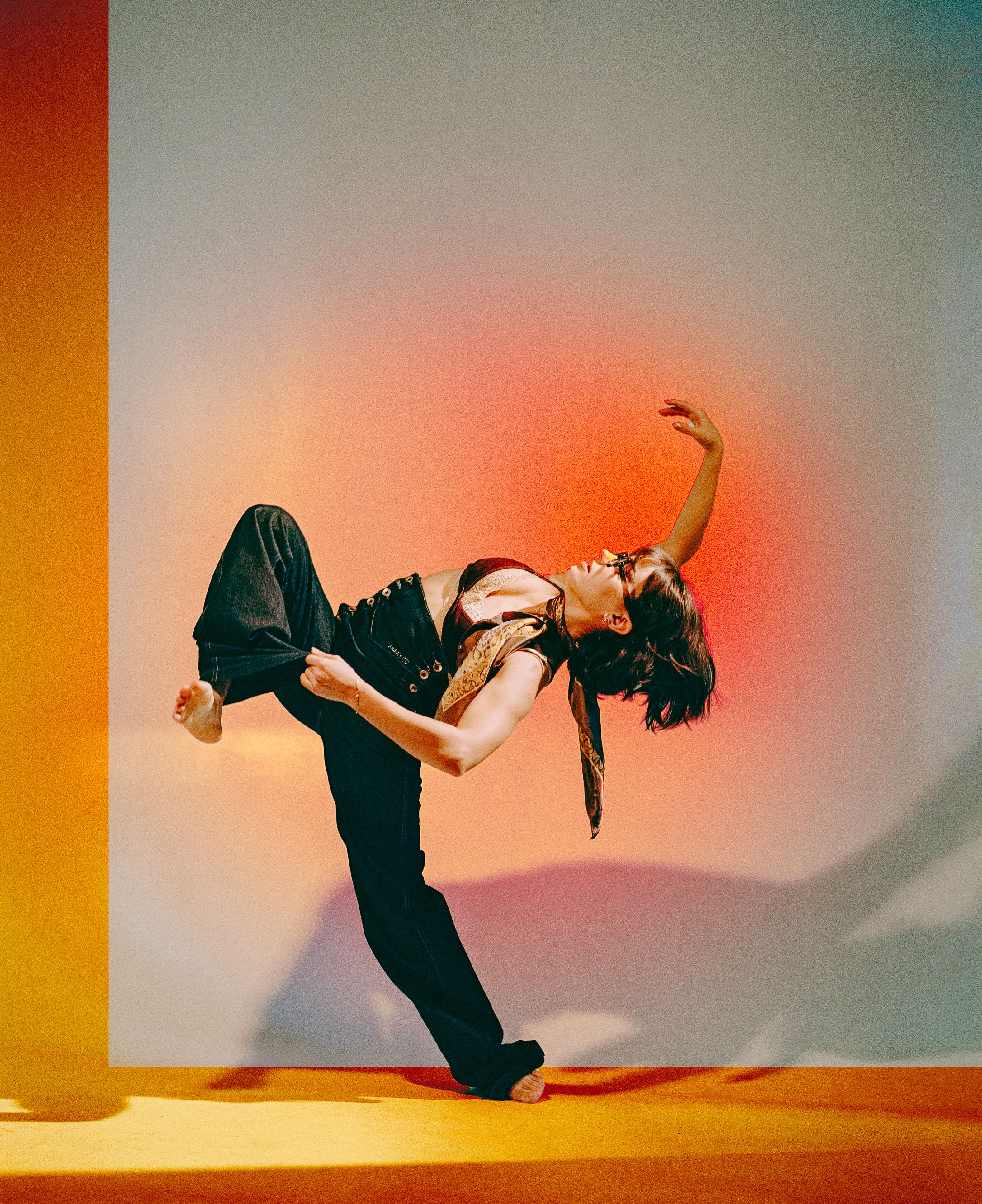 Dynamic dance pose silhouetted against a vibrant orange and pink gradient background.