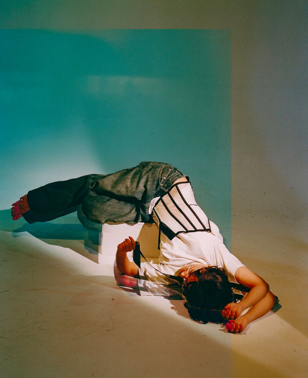 Artistic fashion photo showing model in layered clothing lying down with dramatic lighting.