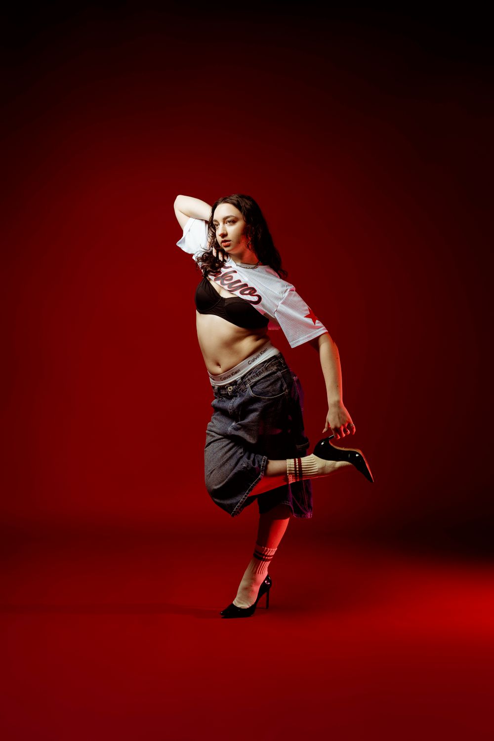 Energetic dance movement captured against deep red studio setting.