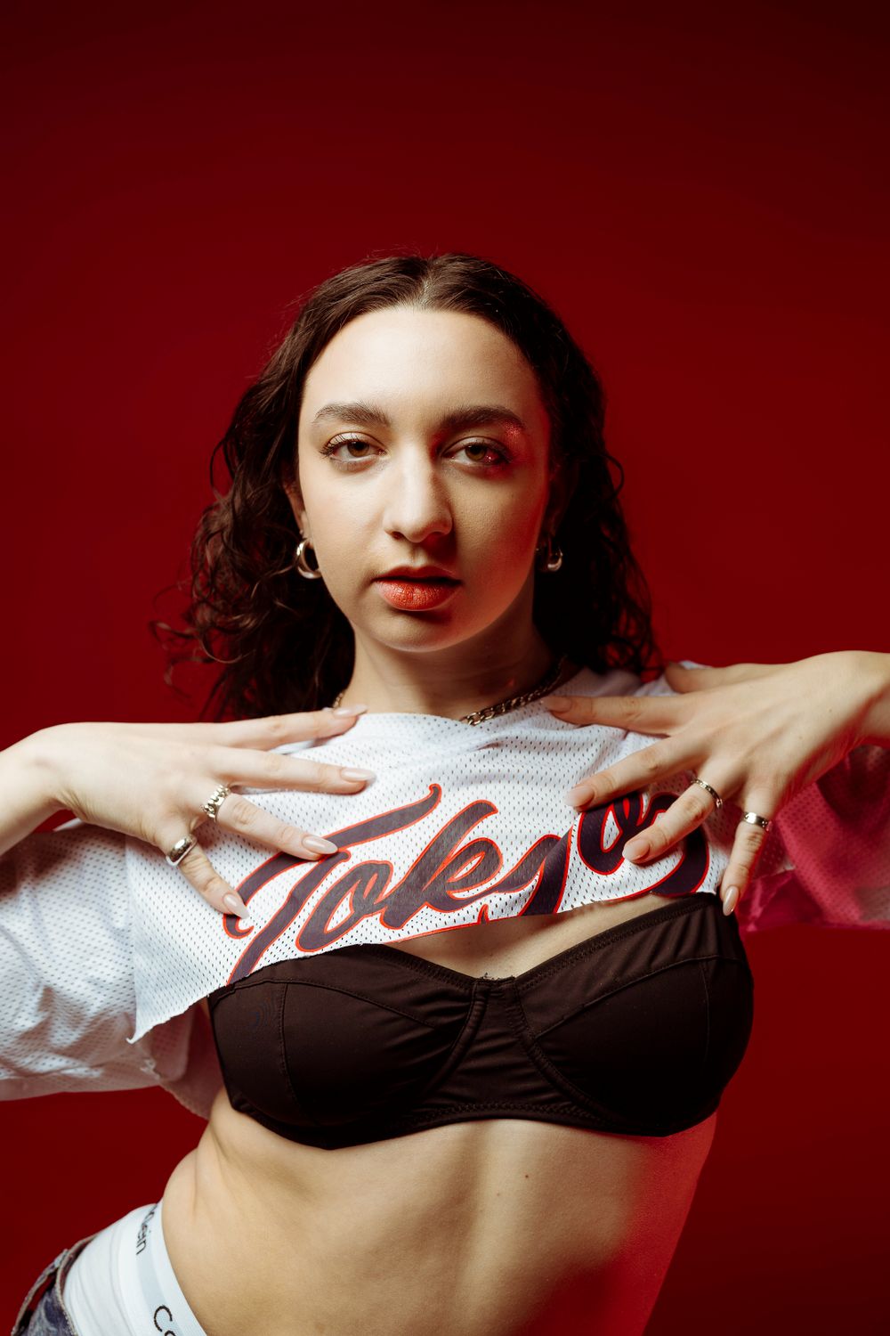 Fashion portrait showcasing Tokyo branded sportswear against red studio backdrop.