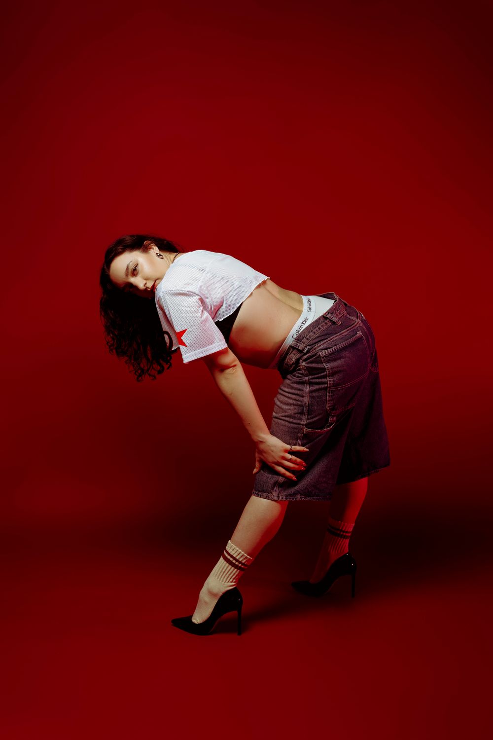 Dynamic pose in sporty crop top and cargo pants with red athletic socks.