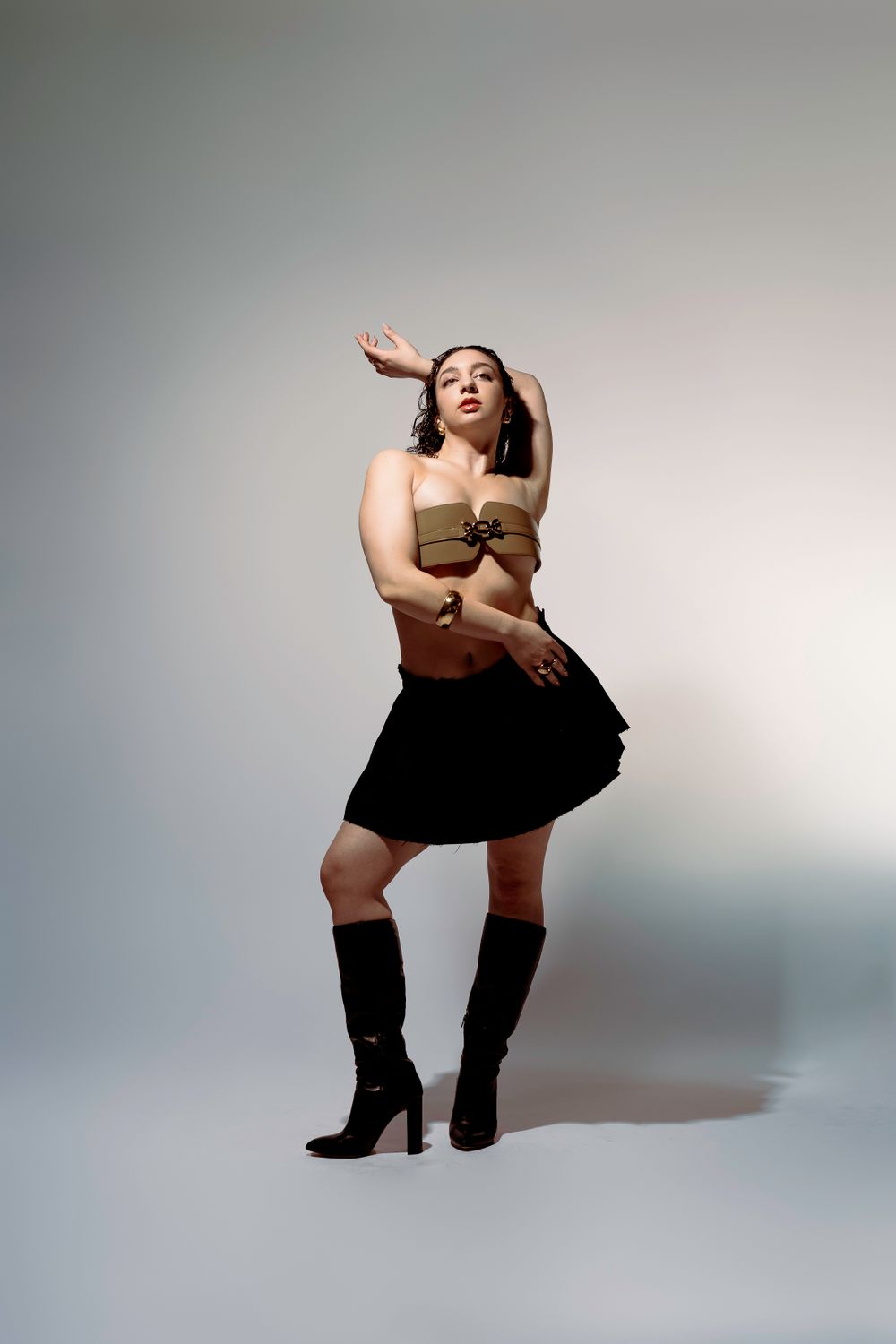 Energetic dance performance pose in two-piece outfit with dramatic studio lighting.