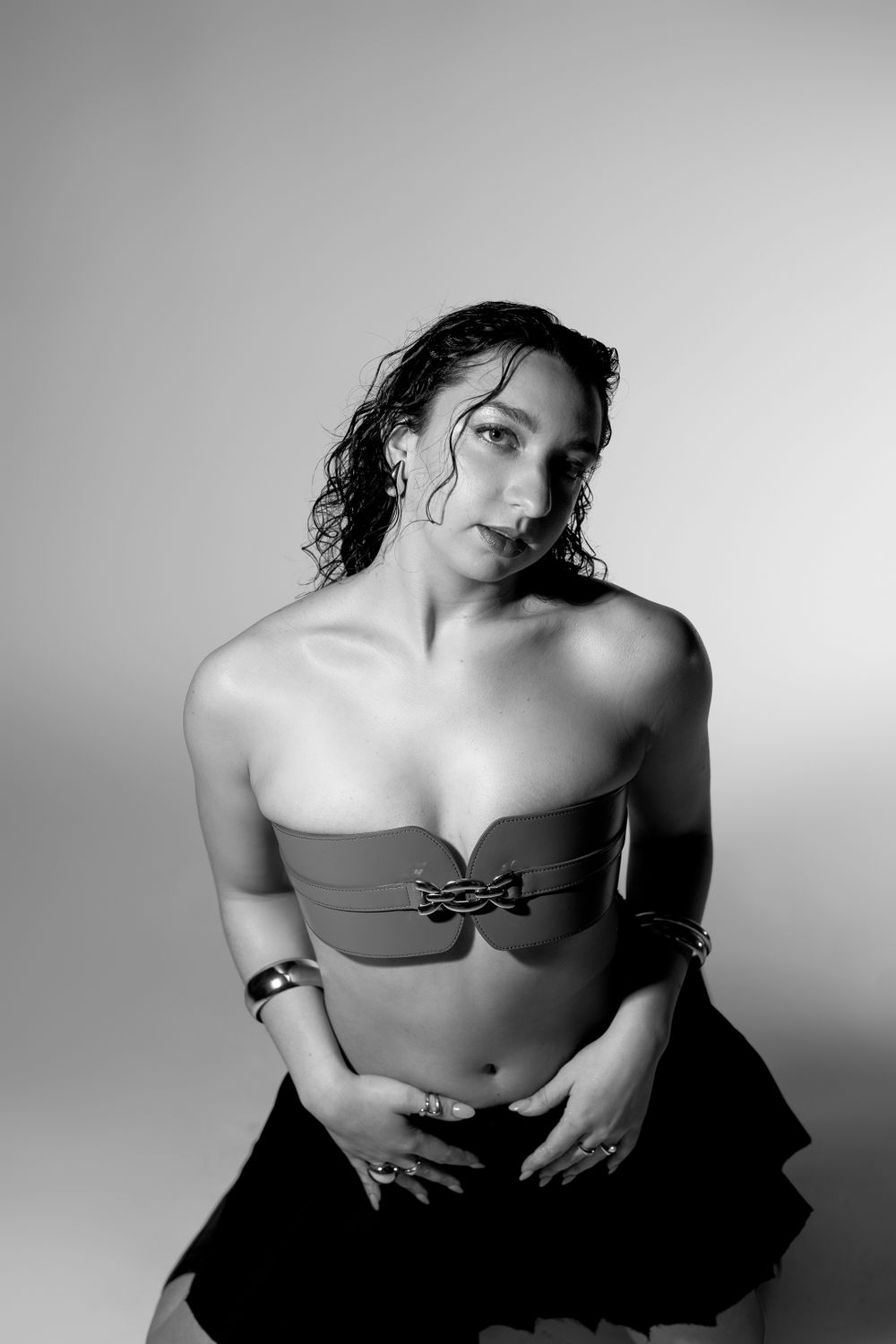 Black and white portrait of model wearing strapless top in artistic studio setting.