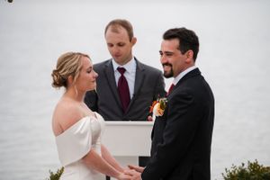 An intimate wedding ceremony moment captured outdoors with three people at the altar.