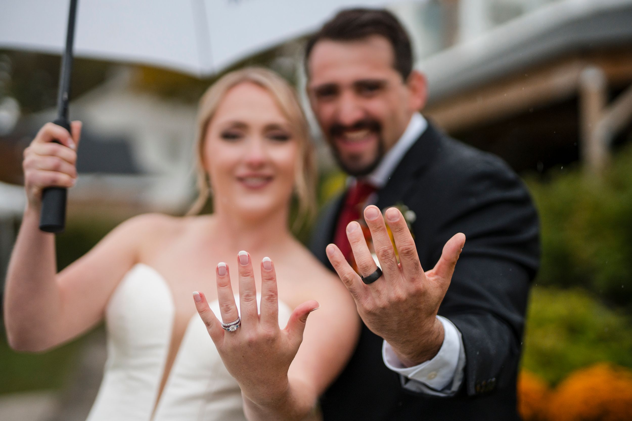 A close-up shot showing wedding rings and hands during an outdoor ceremony.