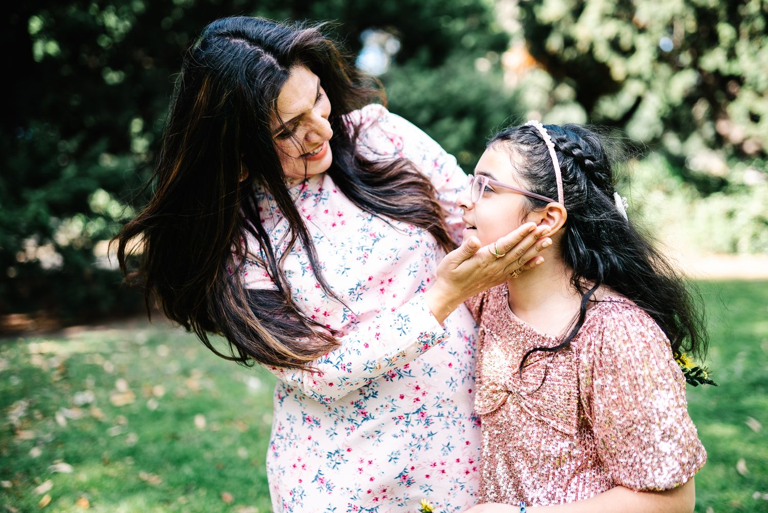 Mother and daughter looking at each other in a family photoshoot in Melbourne's St Kilda Botanical Gardens with lush greeneries as backdrop