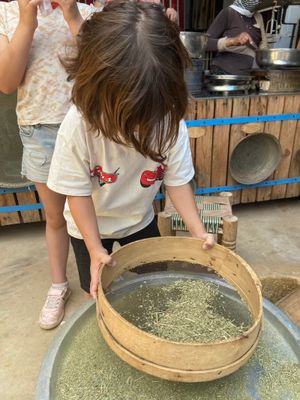 Someone uses a traditional bamboo sieve to sort dried zaatar in a rustic workshop setting.