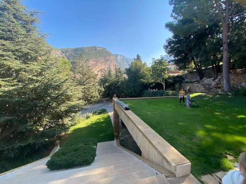 Red rock mountain vista from a landscaped garden terrace with stone retaining walls and green lawn in a natural setting.