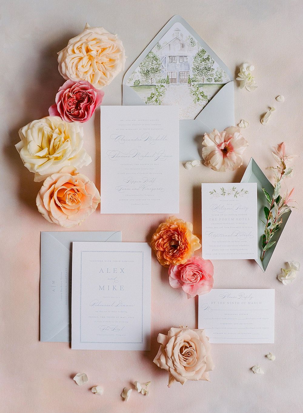 Elegant wedding invitation suite with blush and coral roses arranged around white stationery and a delicate illustrated envelope.