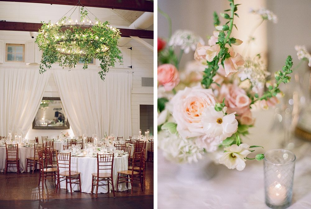 Elegant wedding reception setup featuring sheer white drapes, pink rose centerpieces and a suspended greenery chandelier.