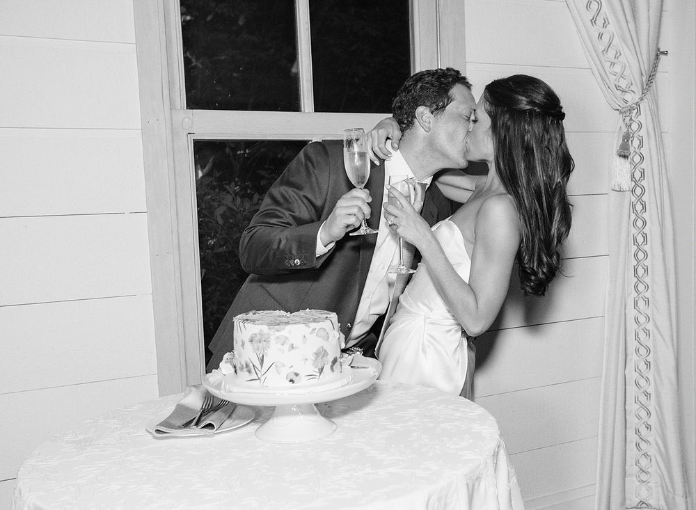 A black and white photo of newlyweds sharing cake during their first bite at a wedding reception.