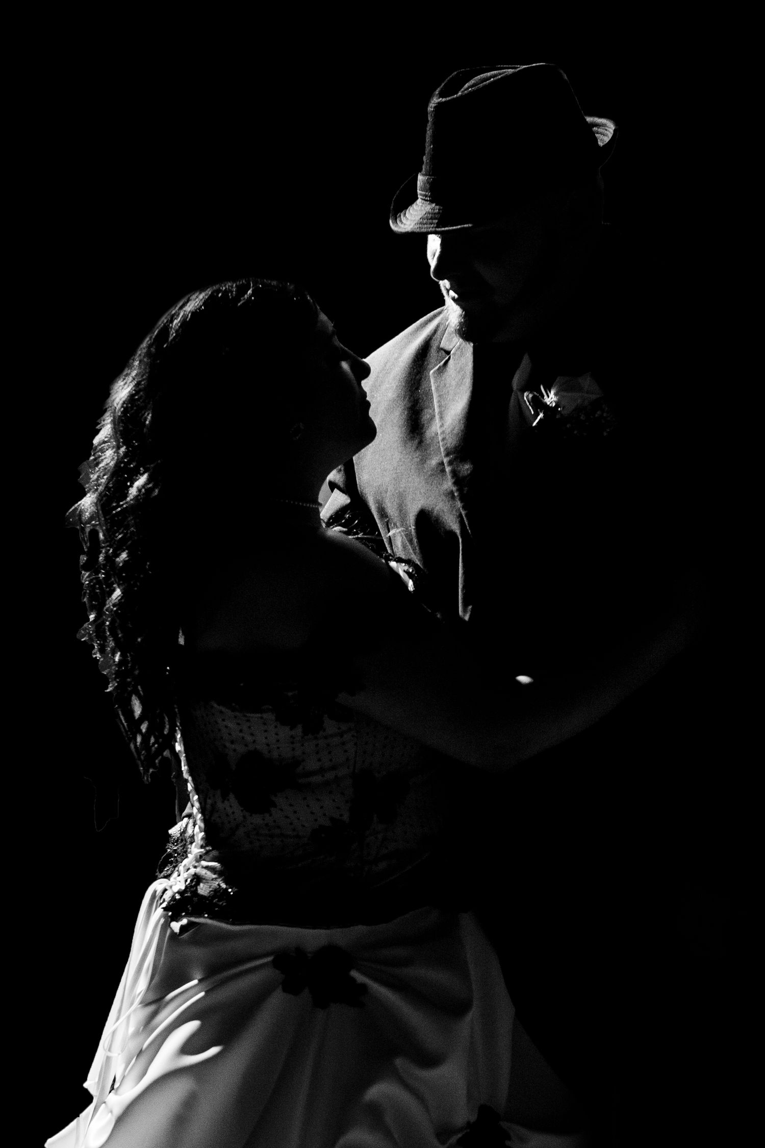 Dramatic black and white silhouette of a dancing couple with man wearing a fedora hat.