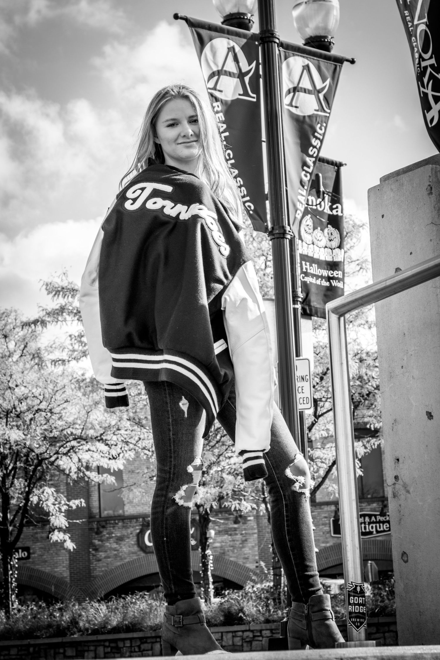 portrait of young girl holding her letterman jacket on the main street of her town