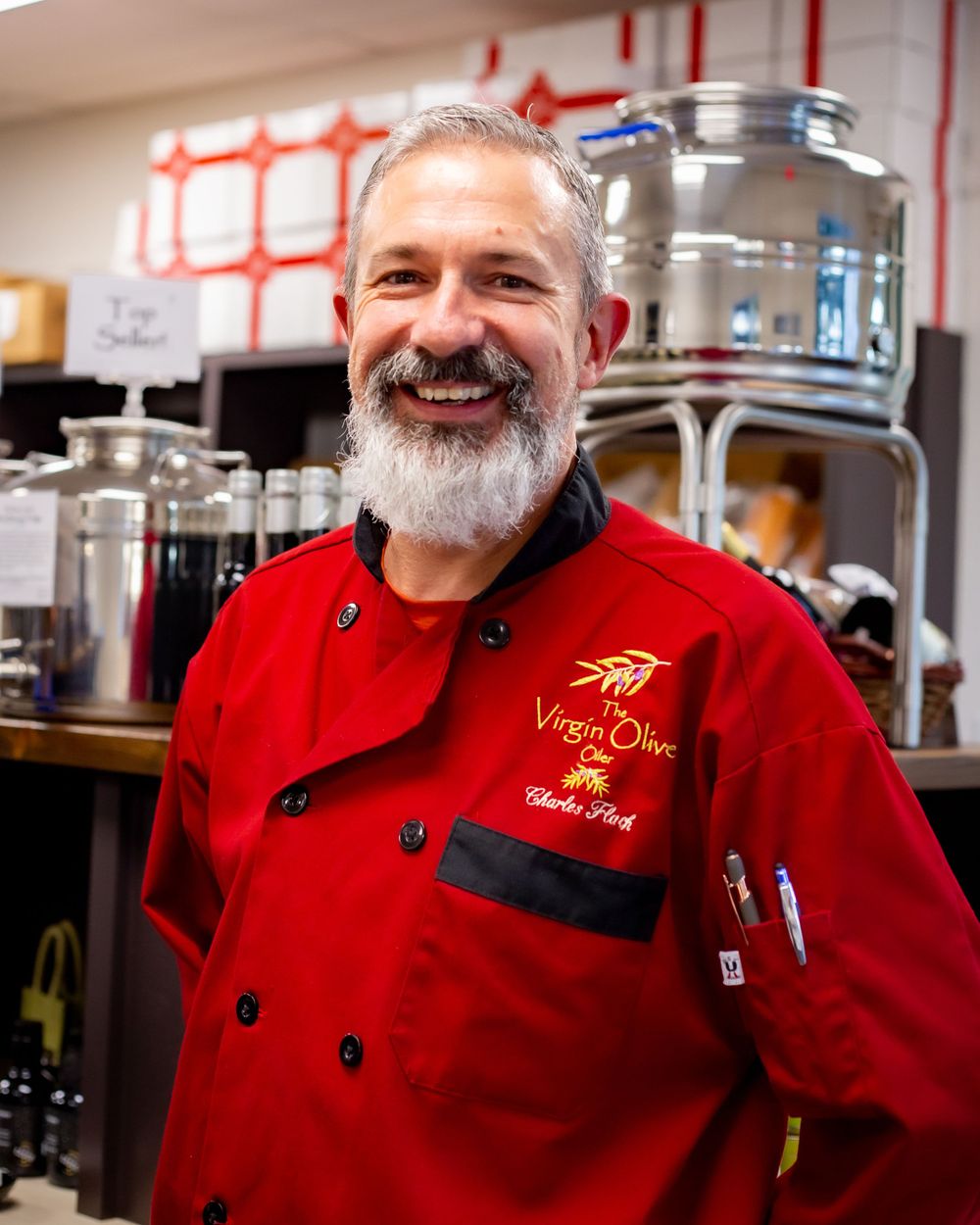 A chef wearing a bright red uniform stands in a professional kitchen environment.