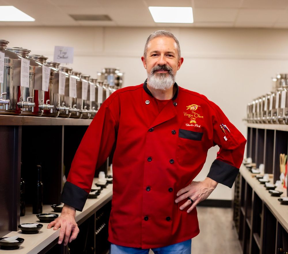 Chef in red uniform standing in a commercial kitchen with stainless steel equipment.