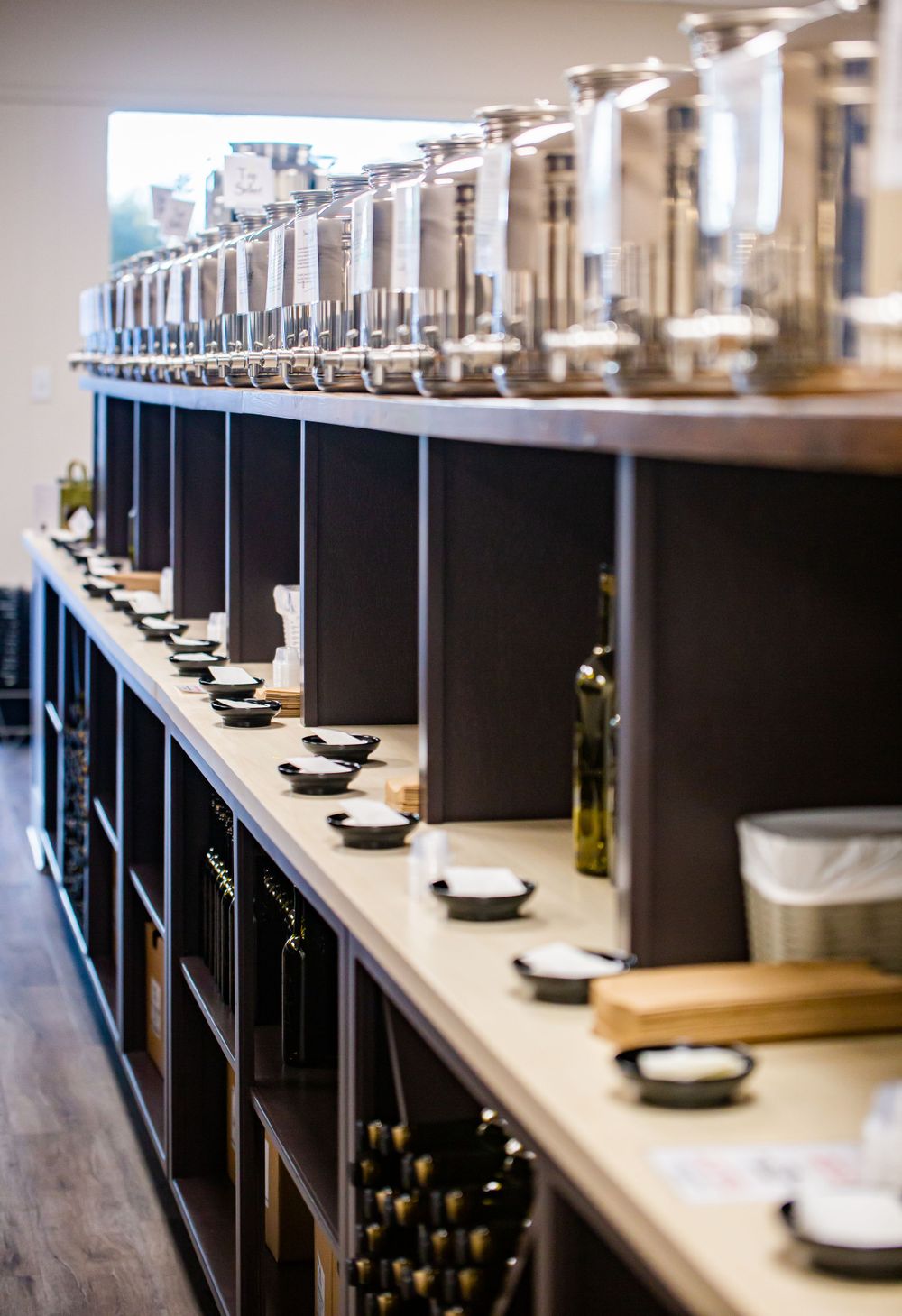 Retail display of olive oil taps mounted on black shelving units.