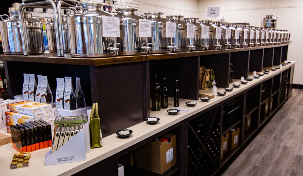 Long rows of olive oil dispensers arranged on dark wooden shelving.
