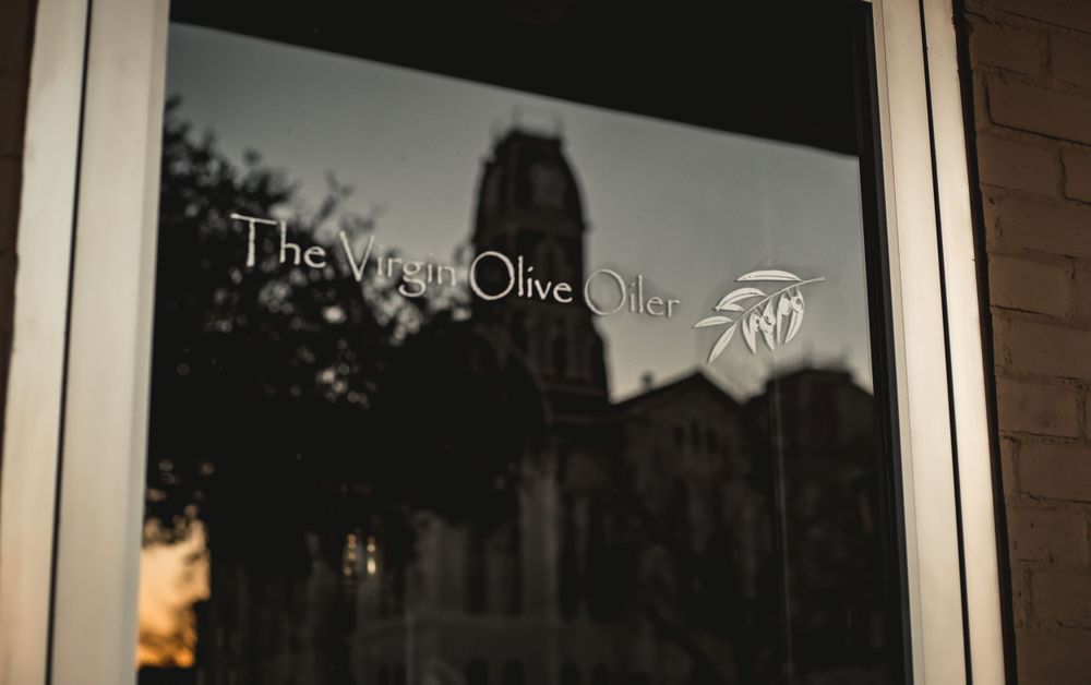 Exterior window view of The Virgin Olive Oil store sign.