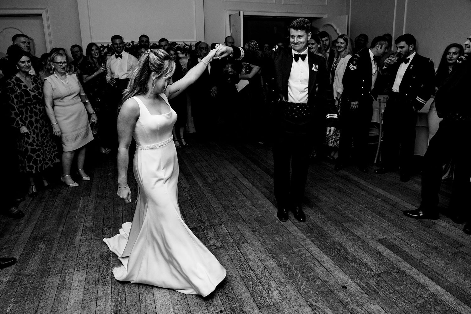 A couple performs their first dance together at The Halifax Hotel wedding reception on a wooden dance floor surrounded by guests.