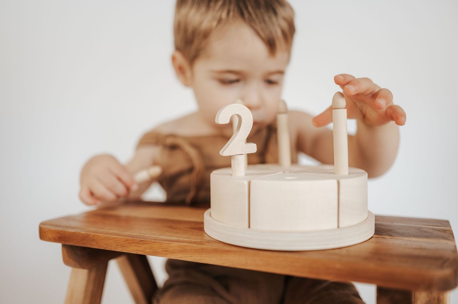 A small white birthday cake with number candles sits on a wooden surface, waiting to be celebrated.