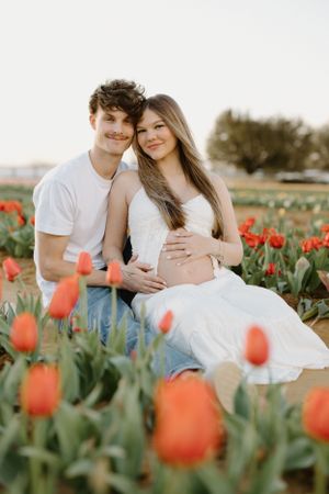 A romantic couple poses together in a blooming tulip field at sunset.