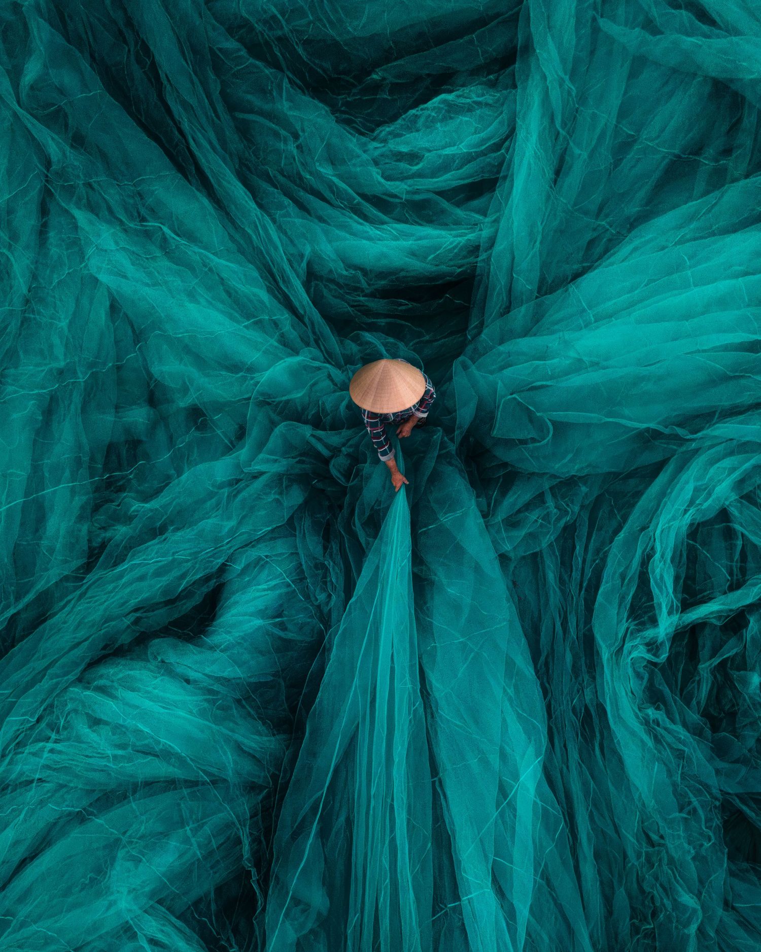 Artistic aerial view of turquoise fabric flowing in circular patterns in Vietnam. Photograph by Chris Ha.