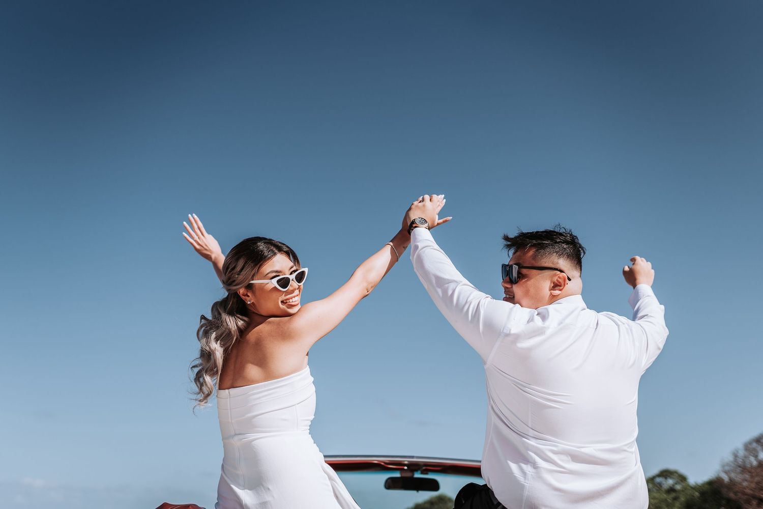 A celebratory moment with hands raised high against a blue sky on a sunny day.