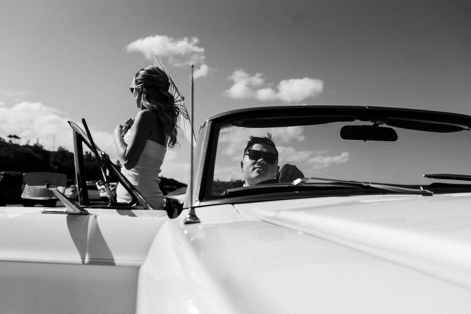 A black and white capture of a retro-styled scene with a classic convertible car.