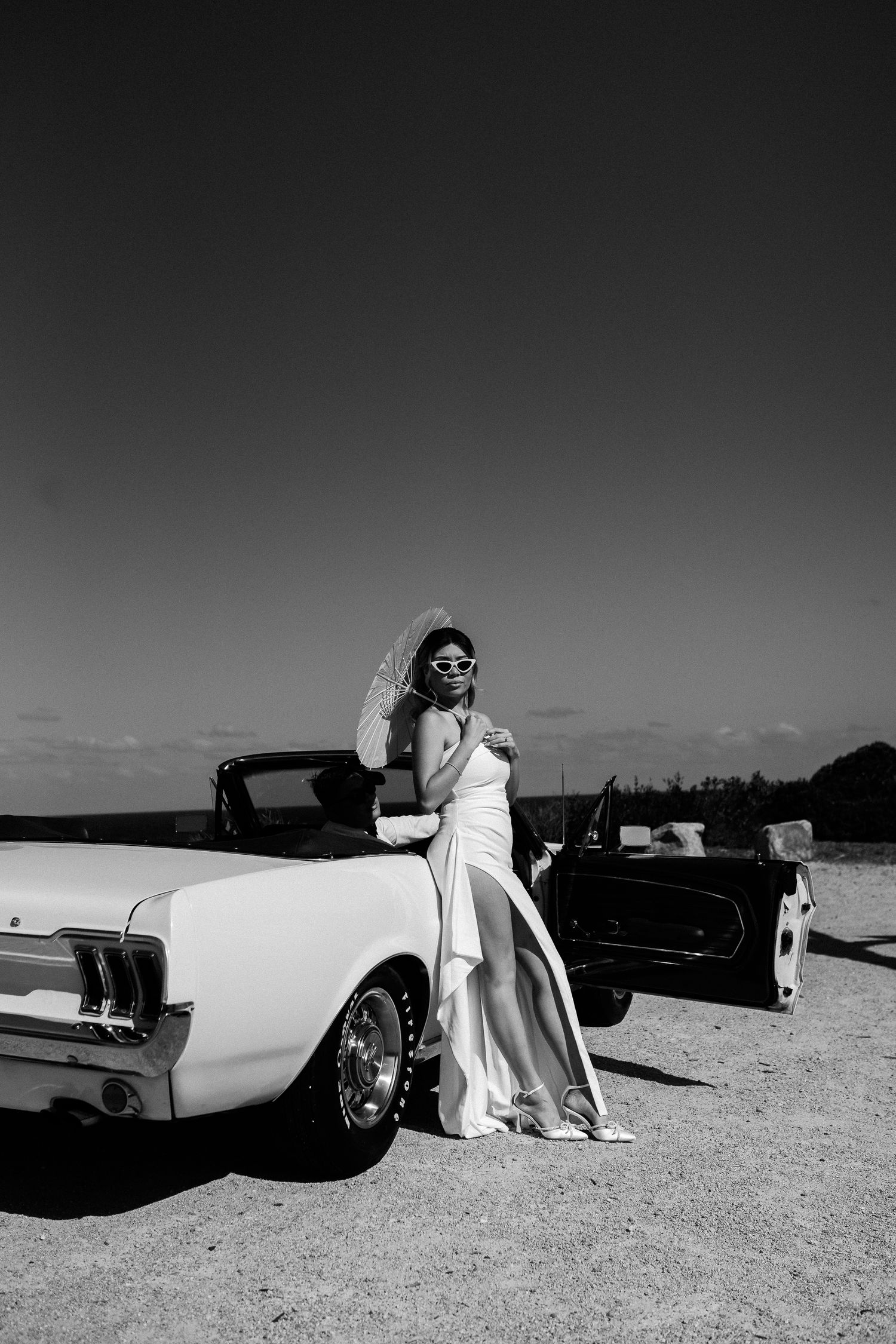 A dramatic black and white portrait with a vintage car against the horizon.