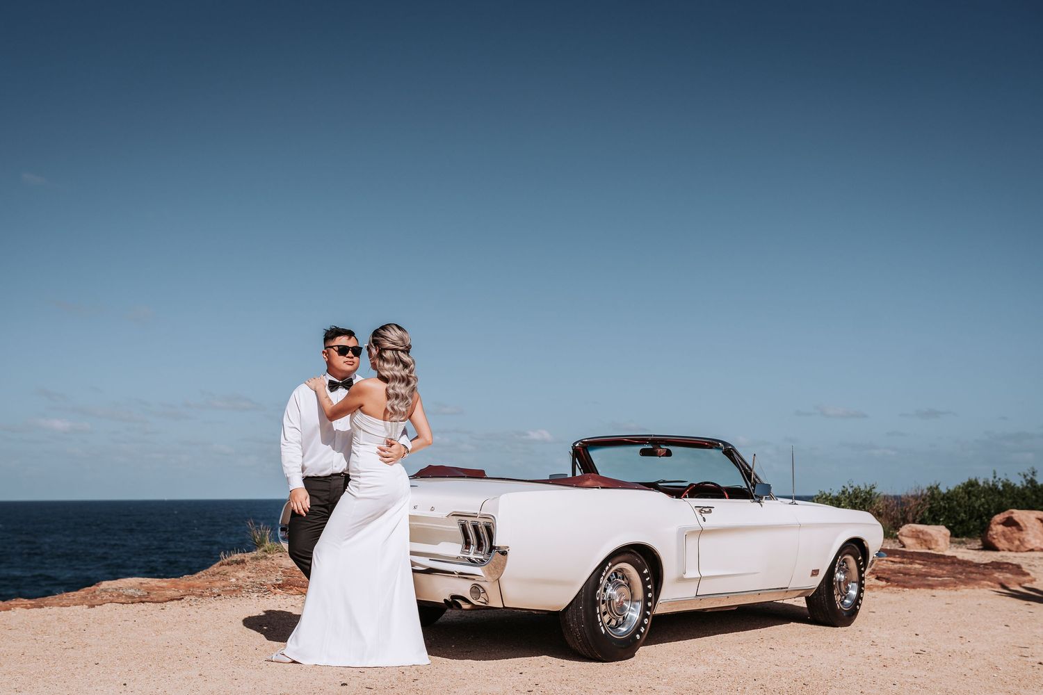 A romantic coastal scene with a classic white convertible car and ocean backdrop.