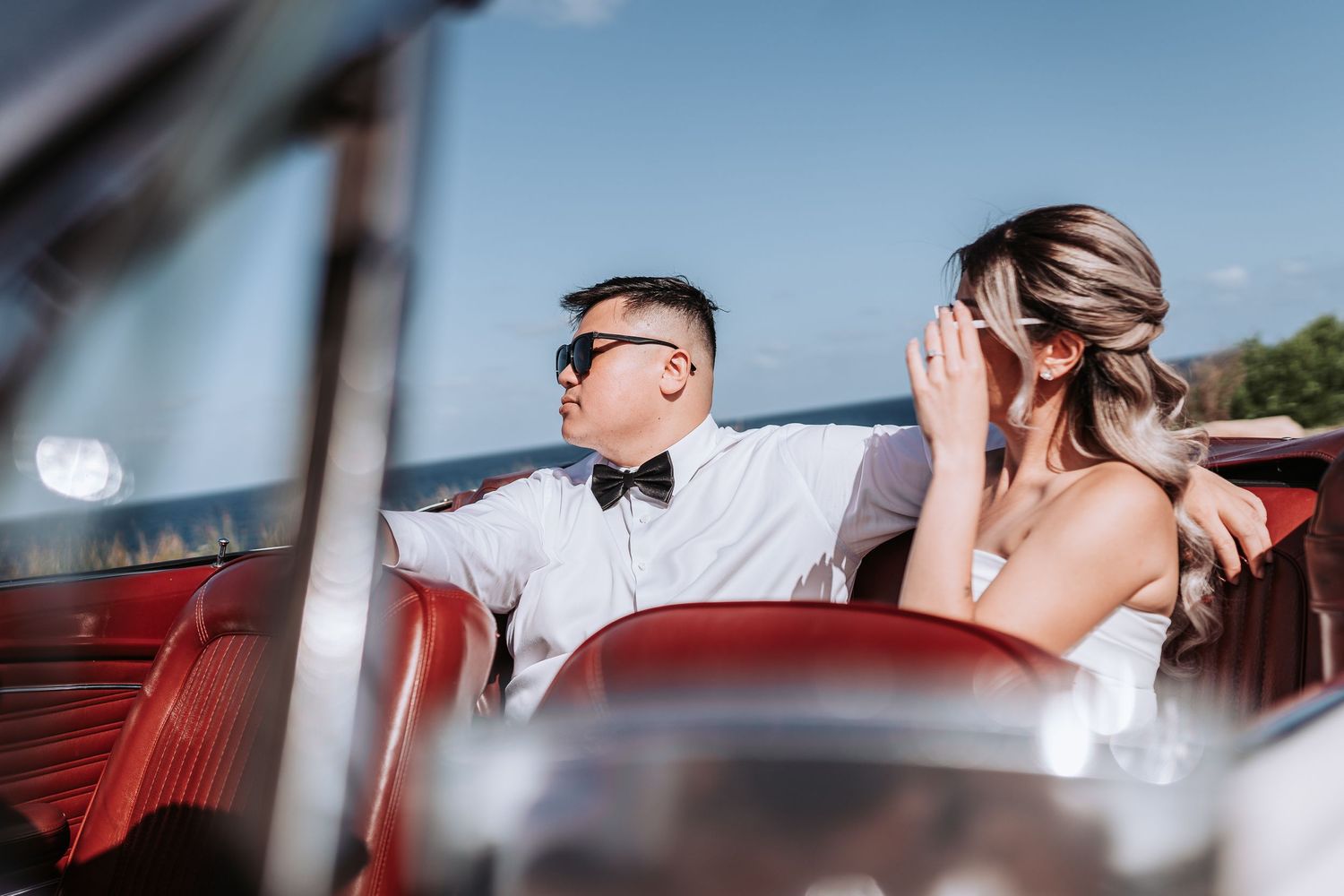 Happy couple enjoying a ride in a classic convertible car by the seaside.