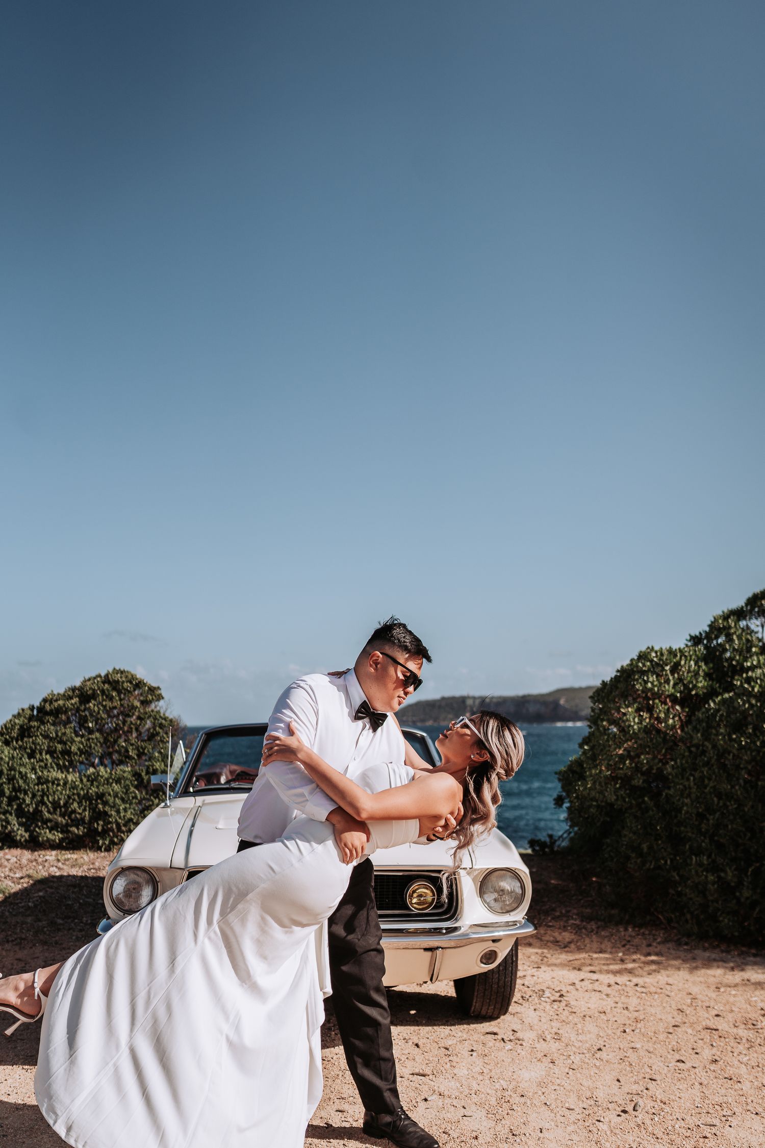 Romantic coastal photoshoot with classic white Mustang car.