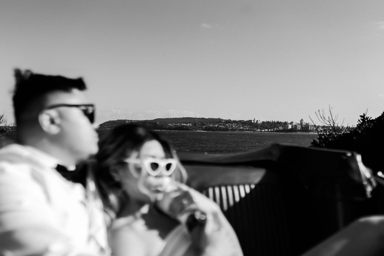 Black and white artistic photo of couple in vintage convertible car.