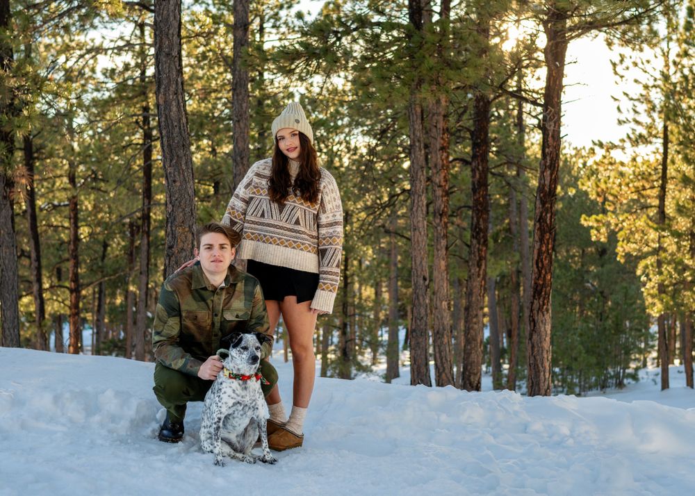 Winter forest portrait with spotted dog and people in casual attire.