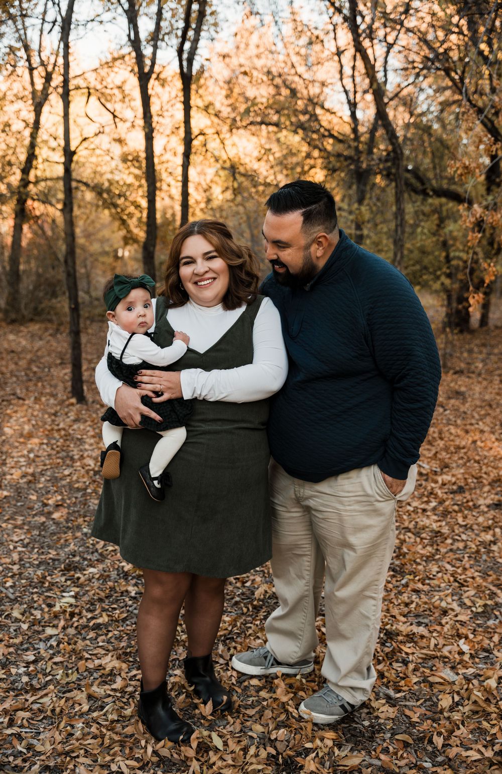 A joyful family photoshoot set in a golden autumn forest with fallen leaves.